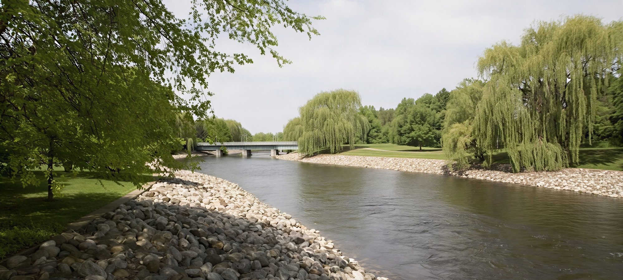 The Battle Creek river running past willows and a footbridge